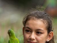 Costaricanisches Mädchen mit Elfenbeinsittich am Finger.